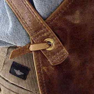Cross-back adjustable straps leather apron, edges are turned and sewn, leather thong tie at the waist. Size 28" x 24.5"